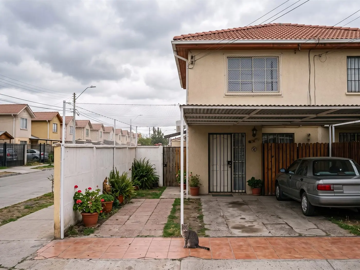 Casa de dos pisos de Maipú con malla entre la pandereta y el techo del cobertizo y en la ventana del segundo piso, con un gato en el patio
