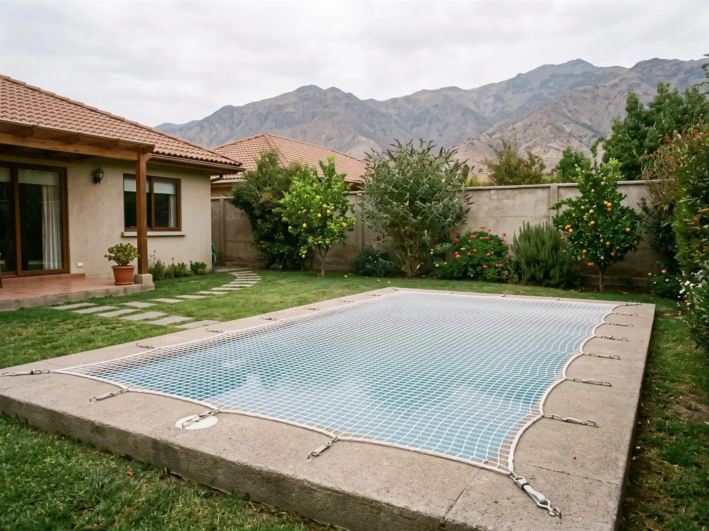 Piscina de una casa de San Bernardo cubierta con malla de seguridad tensada, con el jardín y la cordillera